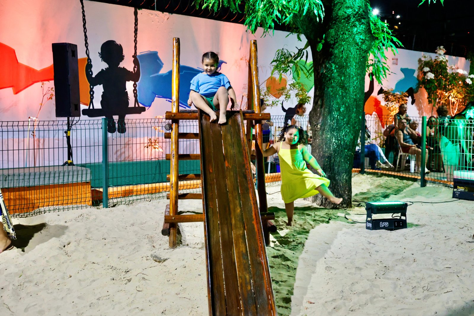 Duas meninas brincando num escorregador na praç